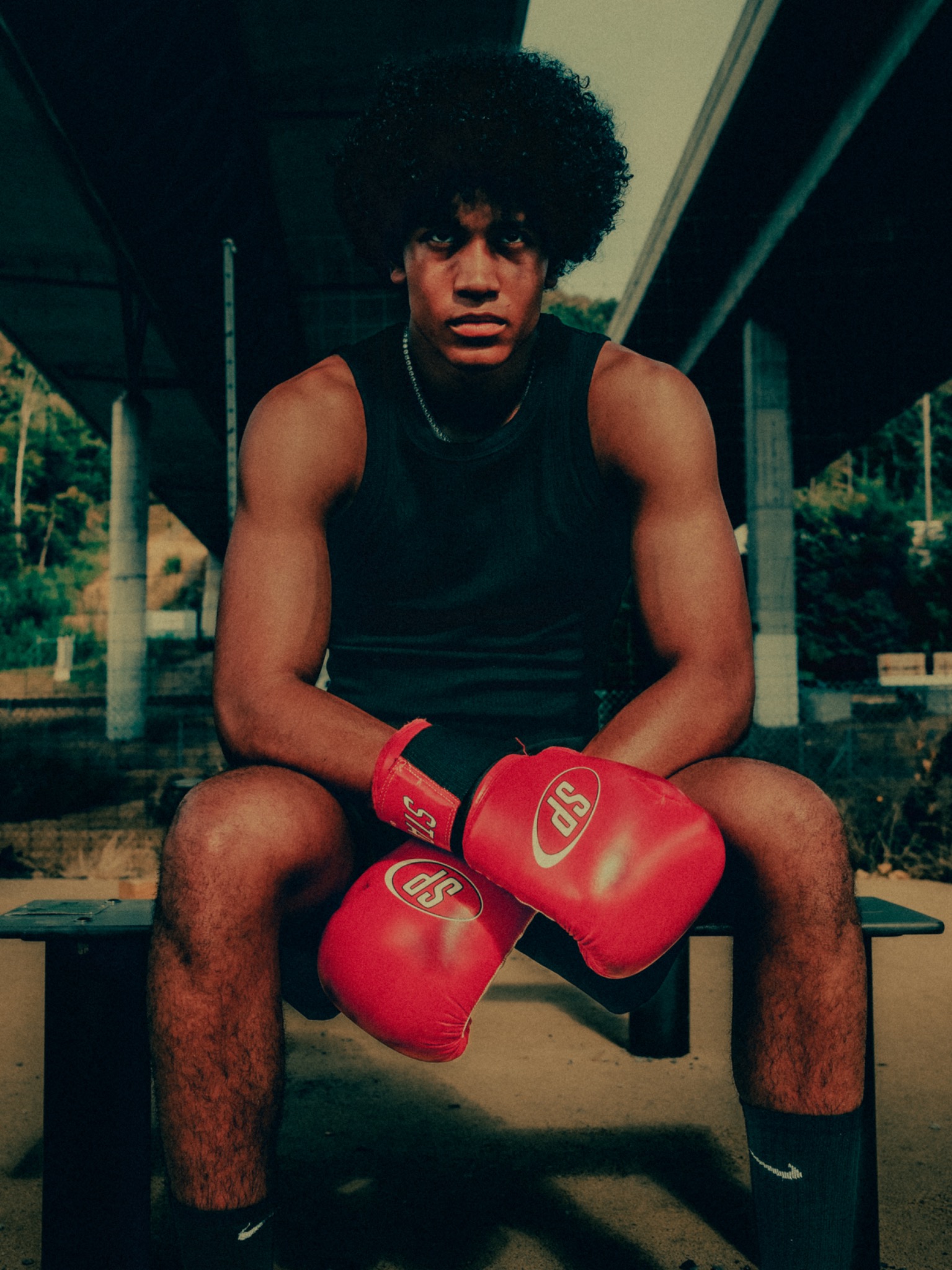 Editorial portrait of a boxer seated with red boxing gloves